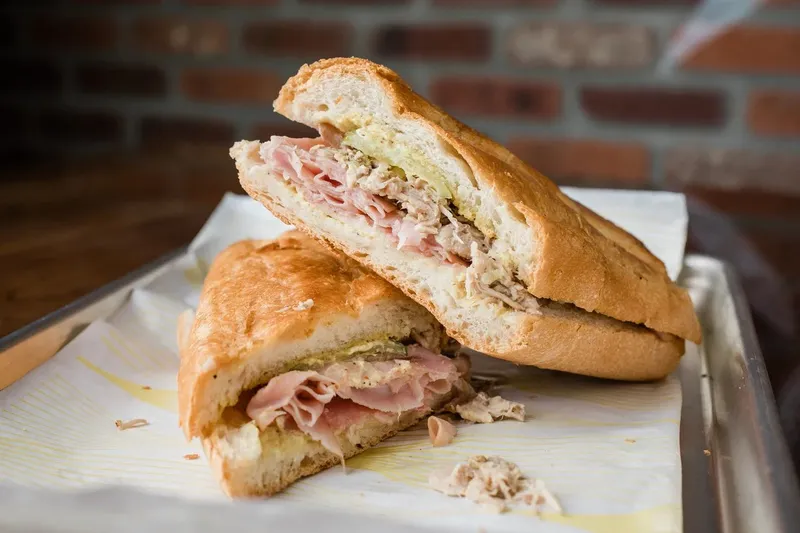 A sliced Cuban sandwich with ham, roast pork and pickles at La Segunda Central Bakery