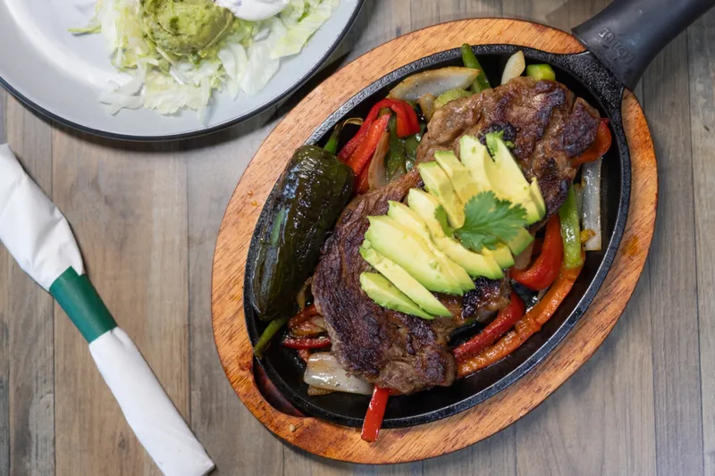 Sizzling fajita skillet topped with avocado at Sancho Panzaa