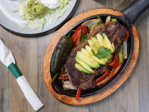 Sizzling fajita skillet topped with avocado at Sancho Panzaa