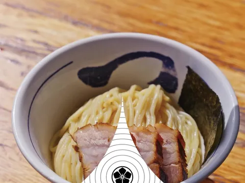 Tsukemen bowl of cold ramen noodles topped with chashu pork slices and nori, with a hand squeezing fresh lime, at Tsujita LA Artisan Noodle
