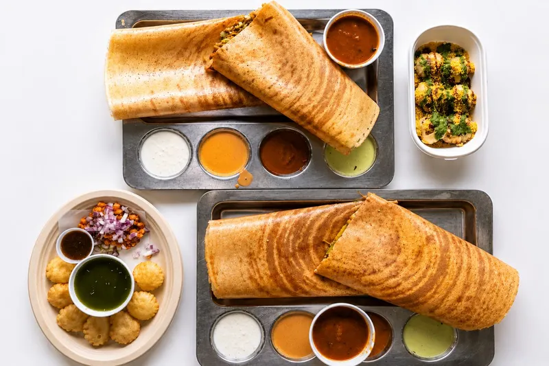 Two dosas on steel trays with sambar, chutneys and chaat at Dosa House in Bellevue.