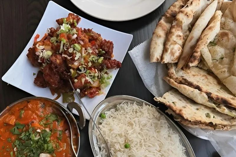 A spread of curries, rice, naan, and fried appetizers at Clay Oven.