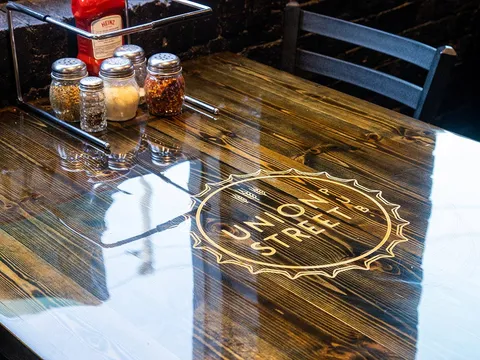 Union Street Pub's logo inlaid in a polished wood tabletop beside a caddy of condiments