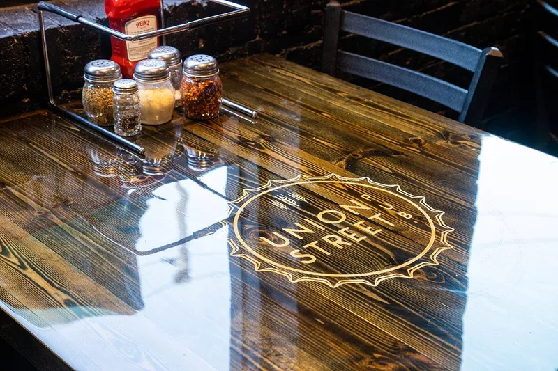 Union Street Pub's logo inlaid in a polished wood tabletop beside a caddy of condiments
