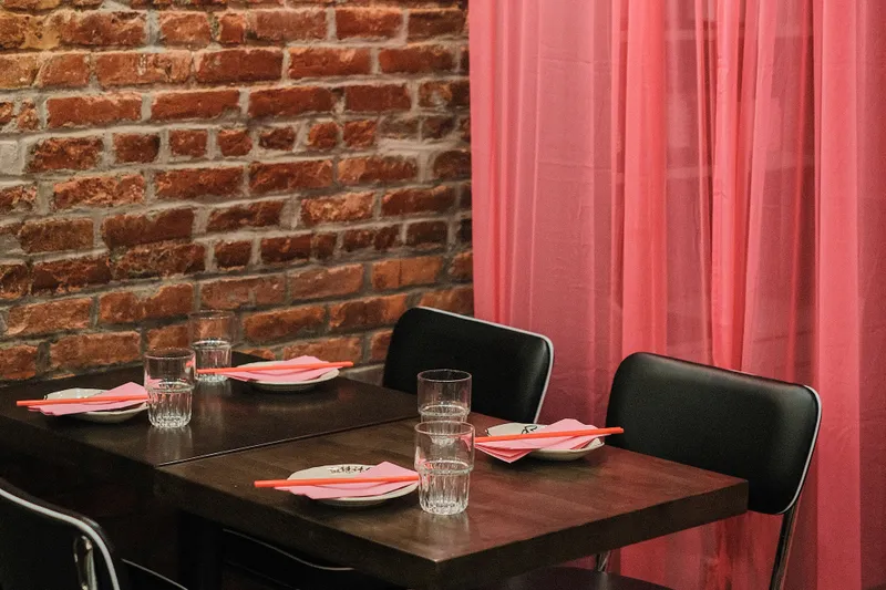 Exposed-brick dining room with a red curtain at Mala Project