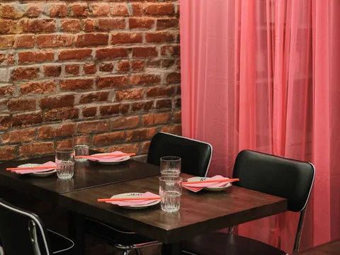 Exposed-brick dining room with a red curtain at Mala Project