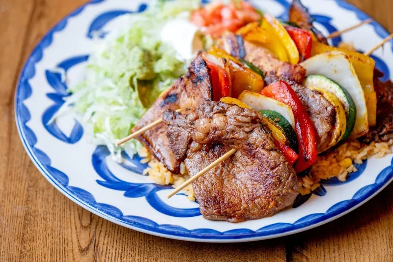 Grilled skewers and steak plated on blue-rimmed talavera-style china at El Rodeo