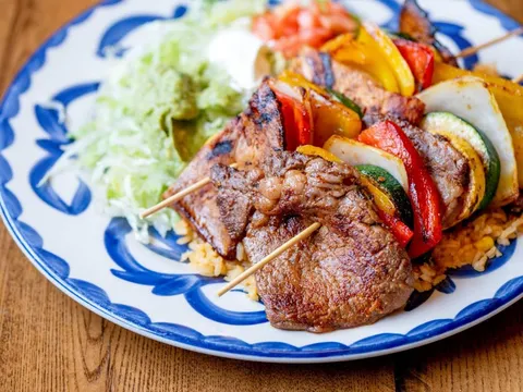 Grilled skewers and steak plated on blue-rimmed talavera-style china at El Rodeo