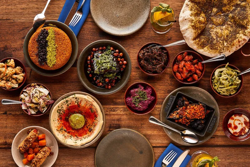 Spread of salatim, hummus, laffa, and lamb shoulder at Zahav
