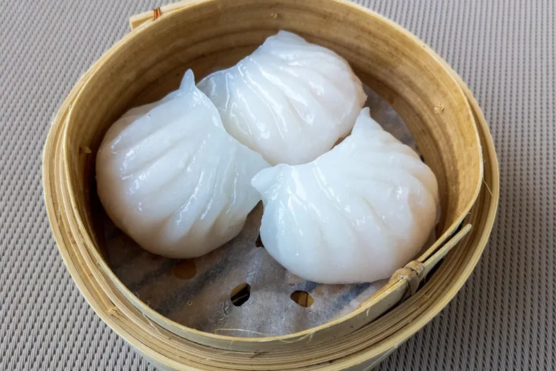 Steamed shrimp har gow dumplings in a bamboo steamer at Furama