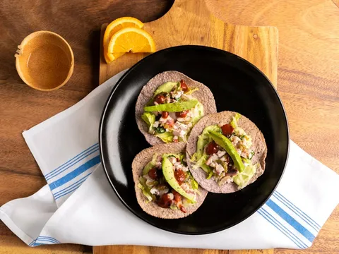 Three tacos arranged on a black plate at Bakan Wynwood