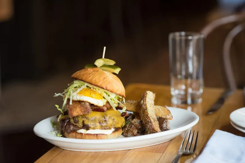 The Heart Stopper Burger topped with a fried egg and bacon, served with fries at The Copper Onion