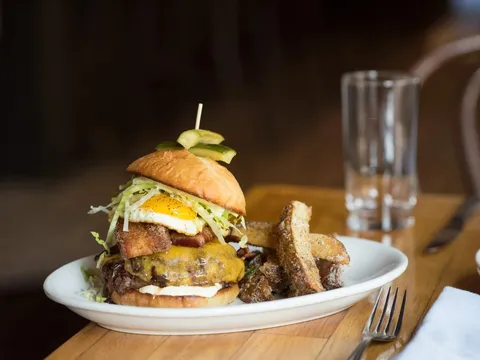 The Heart Stopper Burger topped with a fried egg and bacon, served with fries at The Copper Onion