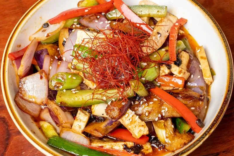 Wok-fried tofu and vegetables with peppers and chili threads in a bowl at Palette Tea House