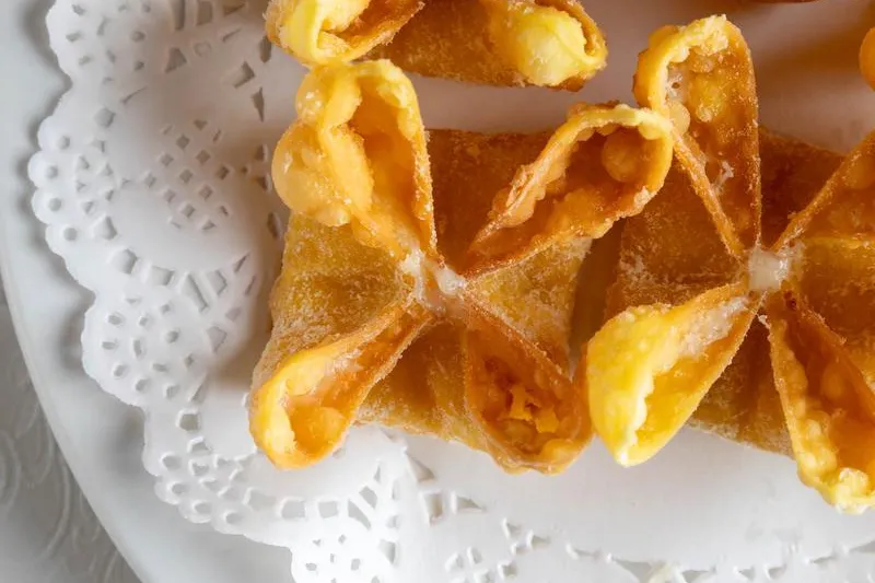 Golden fried crab rangoons on a white plate at Grand Oriental.