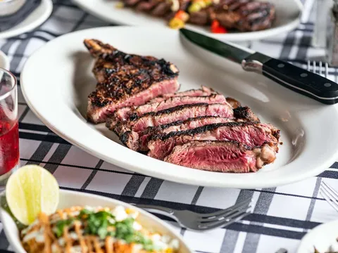 Sliced bone-in ribeye steak on a white plate at Gibsons Bar & Steakhouse in Chicago