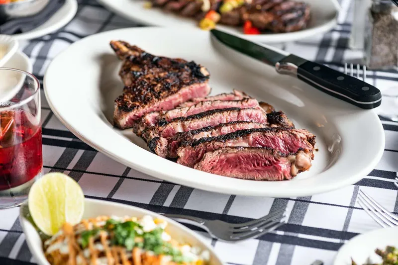 Sliced bone-in ribeye steak on a white plate at Gibsons Bar & Steakhouse in Chicago