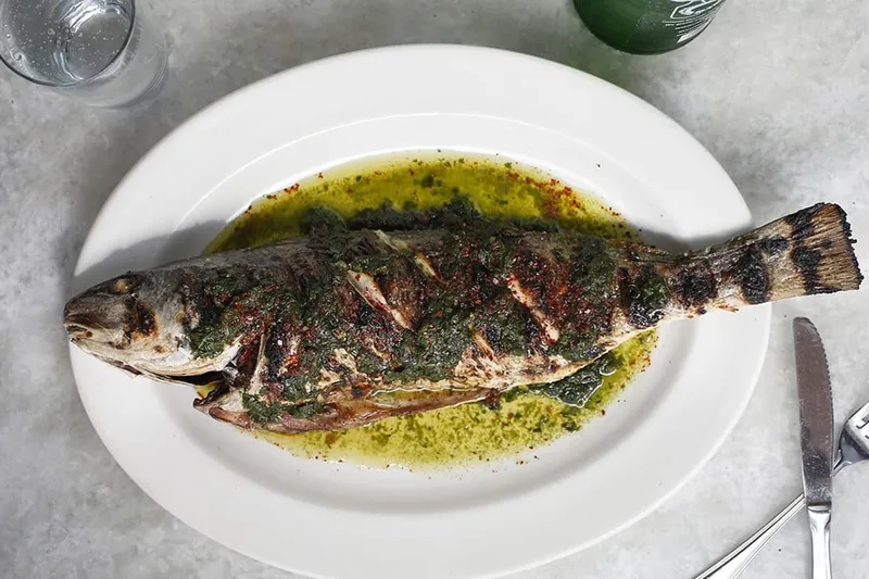 Whole grilled fish served with herb sauce at Pêche Seafood Grill