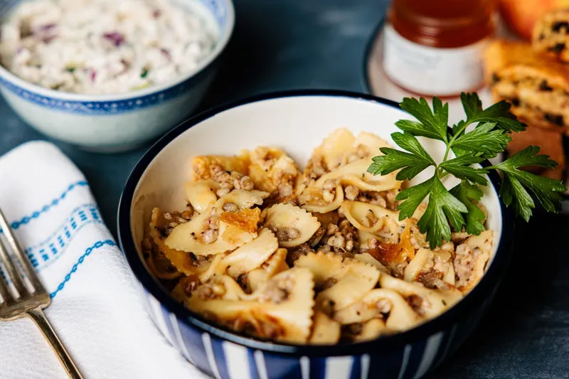 Kasha varnishkes — bow-tie pasta with buckwheat — in a blue-rimmed bowl beside chopped salad and rugelach at Zingerman's Delicatessen