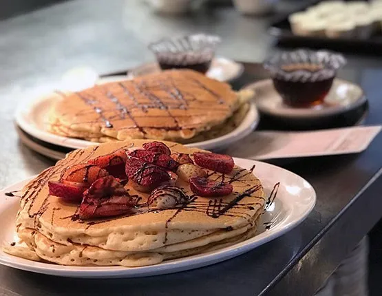 Stacks of strawberry pancakes drizzled with chocolate at Ma Fischer's