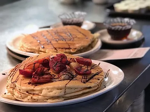 Stacks of strawberry pancakes drizzled with chocolate at Ma Fischer's