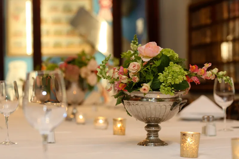 Dining room table with a silver urn floral centerpiece and place settings at Antoine's Restaurant