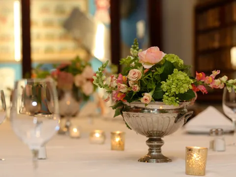 Dining room table with a silver urn floral centerpiece and place settings at Antoine's Restaurant