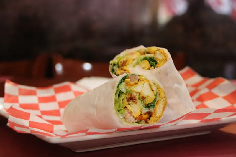 Grilled chicken wrap sliced in half on checkered paper at Kabab Paradise.