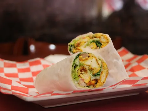 Grilled chicken wrap sliced in half on checkered paper at Kabab Paradise.