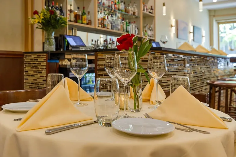 Set table with folded napkins and wine glasses in front of the bar at Cloves Indian Cuisine
