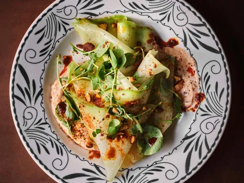 Ribboned green vegetables and herbs on a patterned plate at El Carlos Elegante