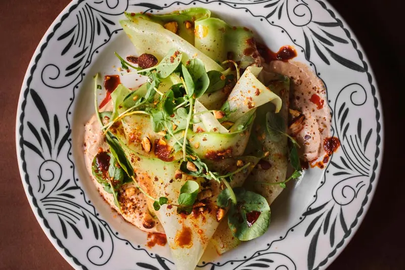 Ribboned green vegetables and herbs on a patterned plate at El Carlos Elegante