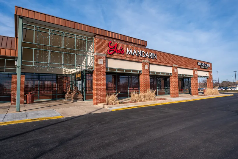Brick storefront with the red 'Yu's Mandarin' sign and stone guardian lions at Yu's Mandarin in Wheeling, IL