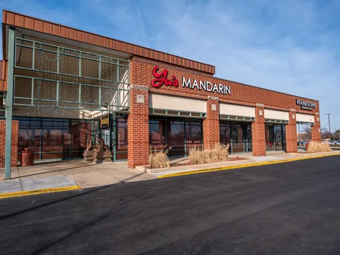 Brick storefront with the red 'Yu's Mandarin' sign and stone guardian lions at Yu's Mandarin in Wheeling, IL