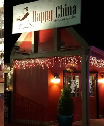 Nighttime storefront of Happy China in Durham, with its 'Happy China - Sichuan cuisine' sign over a red-painted entrance strung with icicle lights and a gold lantern