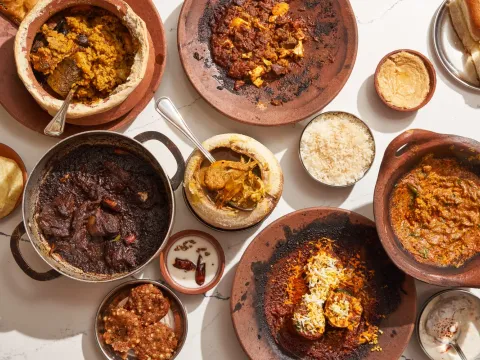 A spread of dishes at Masalawala & Sons in Brooklyn — biryani, dark braised meat, curries and dal in clay and steel vessels with rice, pao and papad