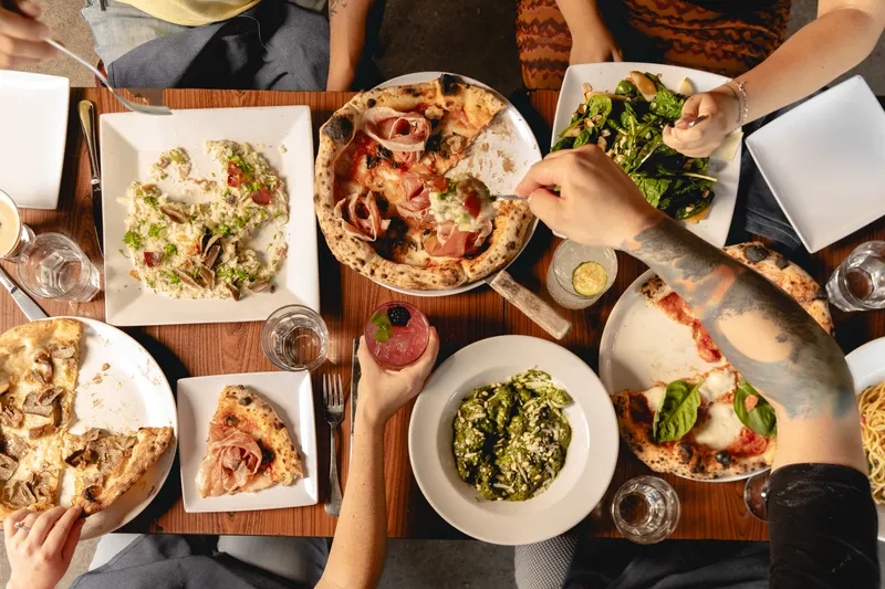 Table spread of pizza, pasta, and salad at Buona Forchetta