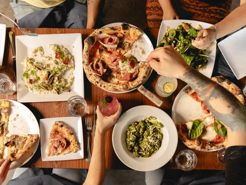 Table spread of pizza, pasta, and salad at Buona Forchetta