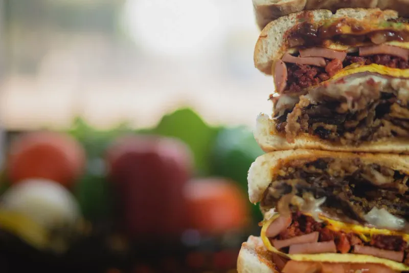 Towering stack of sliced tortas showing layered meats, cheese and vegetables at Los Reyes de la Torta