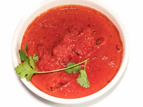 White bowl of deep red curry garnished with cilantro at The Oven