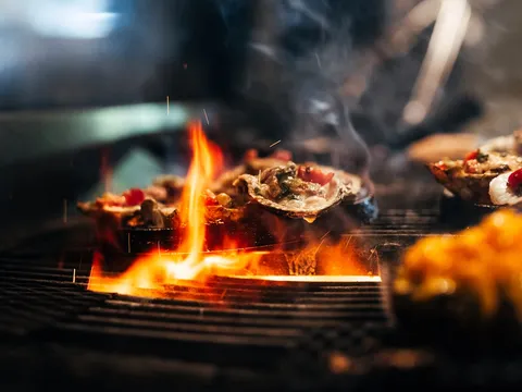Char-grilled oysters cooking over an open flame at Boathouse Rotisserie & Raw Bar