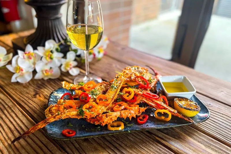 Grilled seafood platter with sliced chiles and a glass of white wine on a wood table at Tequila 61 in Anchorage, Alaska