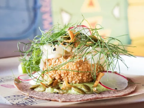 Crisp tostada with greens and radish on a pink corn tortilla at Nixta Taqueria