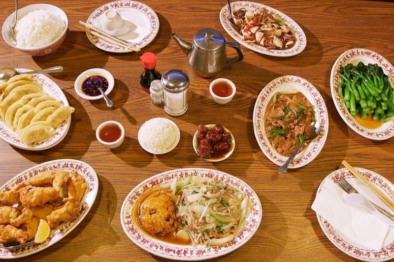Overhead spread of Tai Tung dishes — pot stickers, fried shrimp, greens, chow mein, rice and teapot on the restaurant's classic red-rimmed plates
