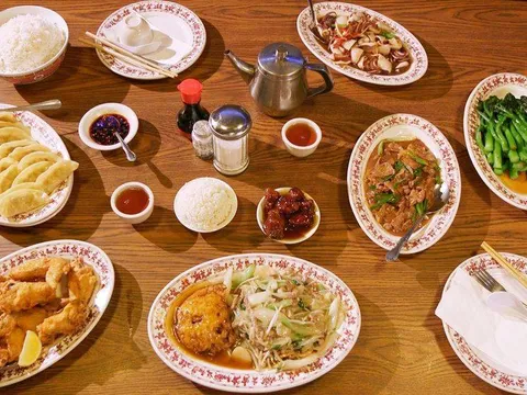 Overhead spread of Tai Tung dishes — pot stickers, fried shrimp, greens, chow mein, rice and teapot on the restaurant's classic red-rimmed plates