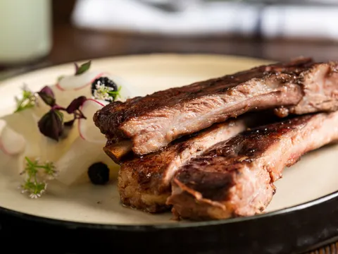 Grilled ribs plated with pickled radish and herbs at Harbinger