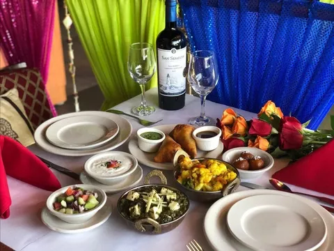 Table spread of samosas, saag paneer, aloo gobi, raita and gulab jamun at All India Cafe in Pasadena