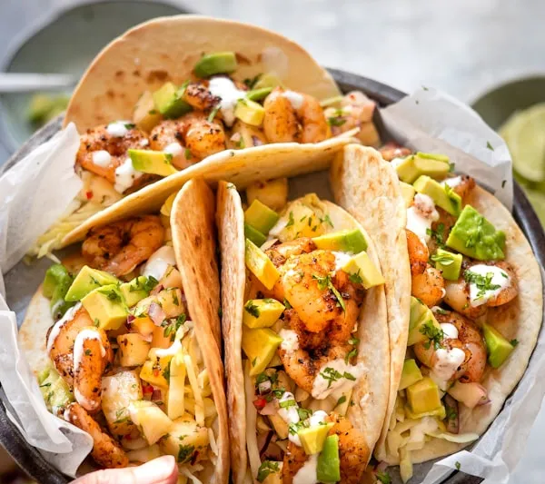 Tray of classic yellow-cheddar hard-shell beef tacos with fresh salsa and chips at Tito's Tacos