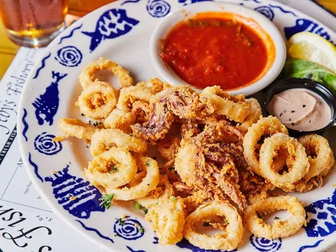 Plate of fried calamari with marinara and tartar sauce on Feby's Fishery's blue-and-white china