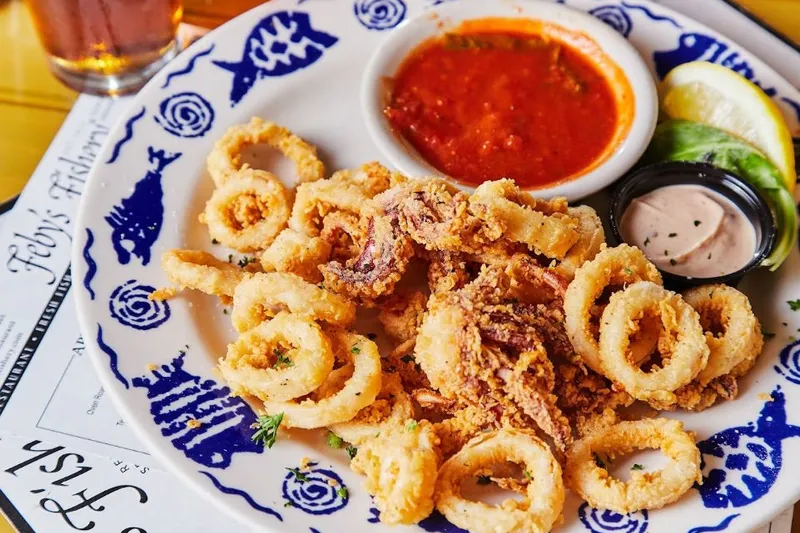 Plate of fried calamari with marinara and tartar sauce on Feby's Fishery's blue-and-white china
